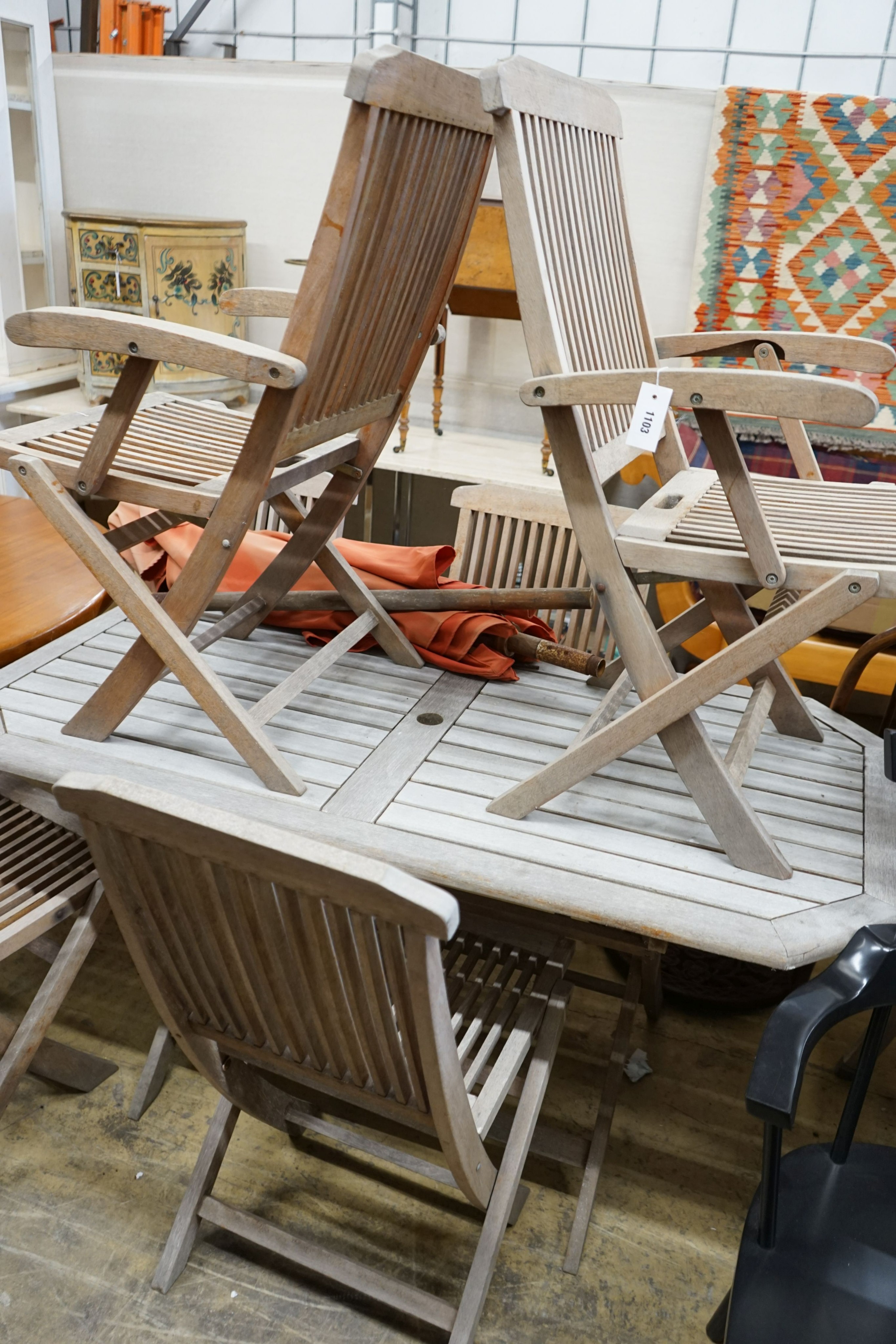 A rectangular weathered teak slatted garden table, length 150cm, depth 79cm, height 72cm, six teak folding chairs, two with arms, parasol and base